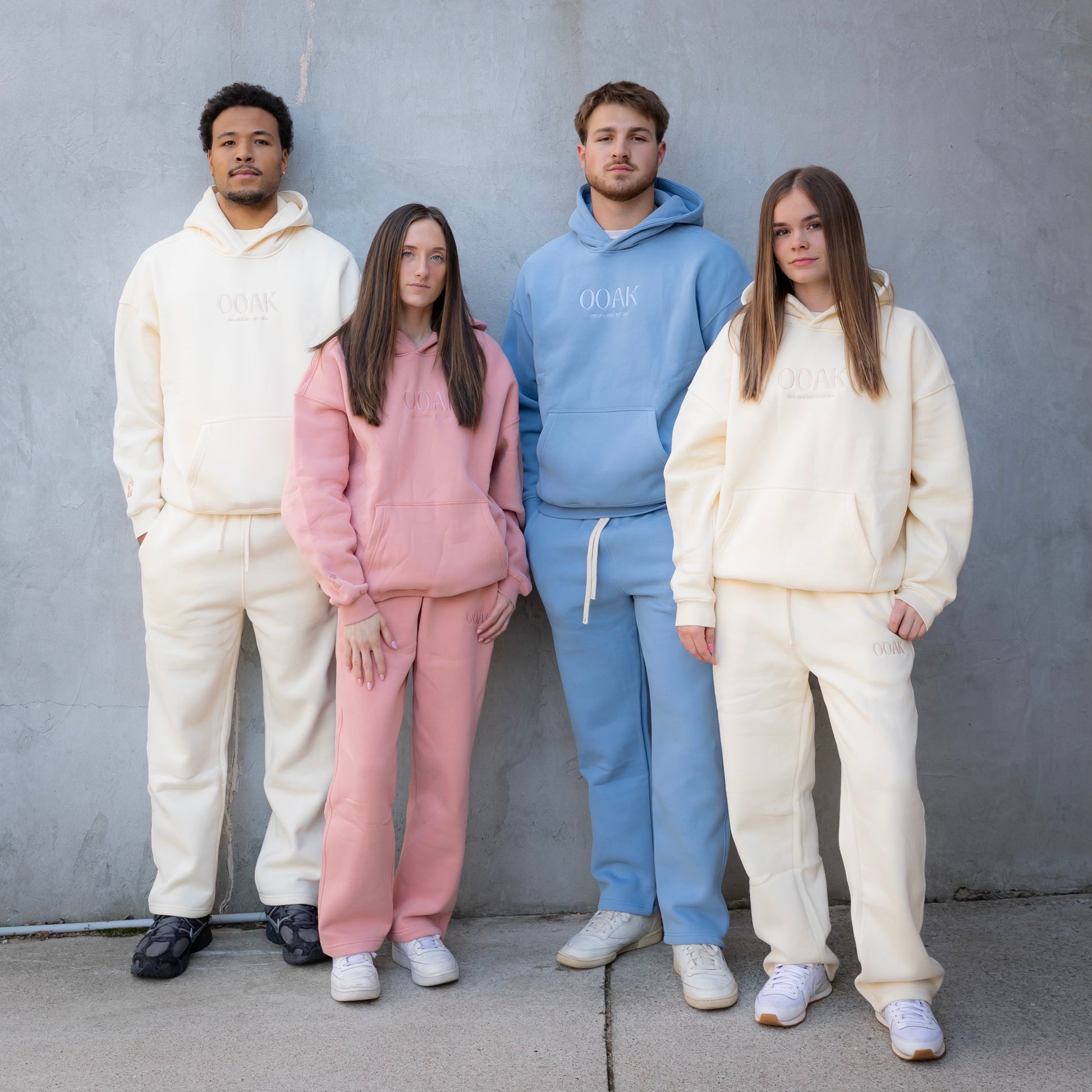 Four people wearing matching outfits in front of a gray wall