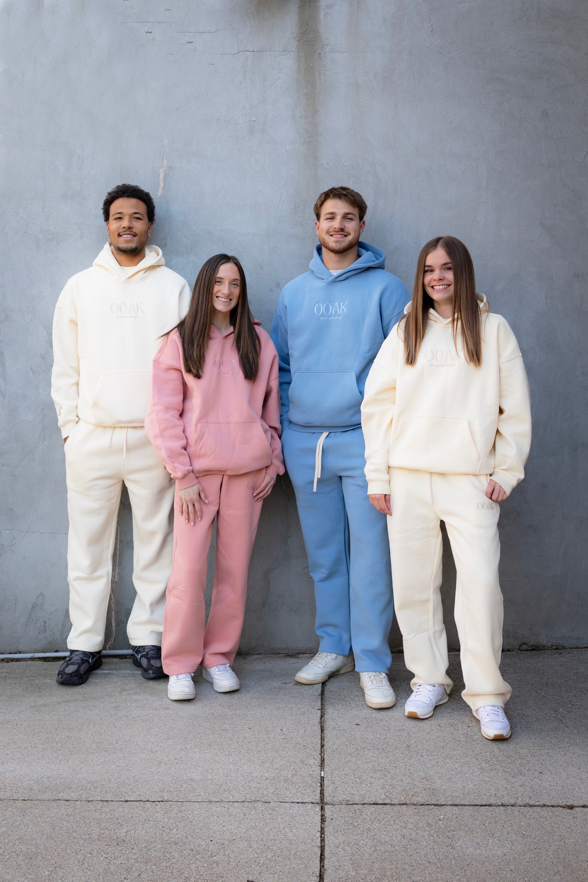 Four people wearing matching outfits in front of a gray wall.