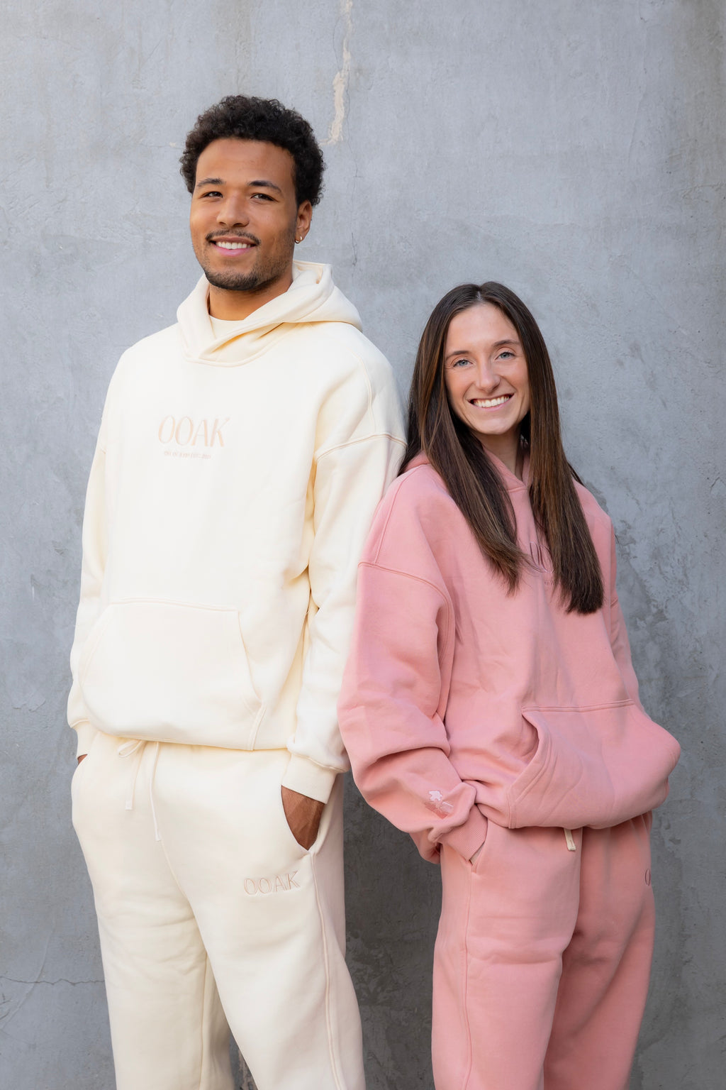 Two people wearing matching outfits in front of a gray wall