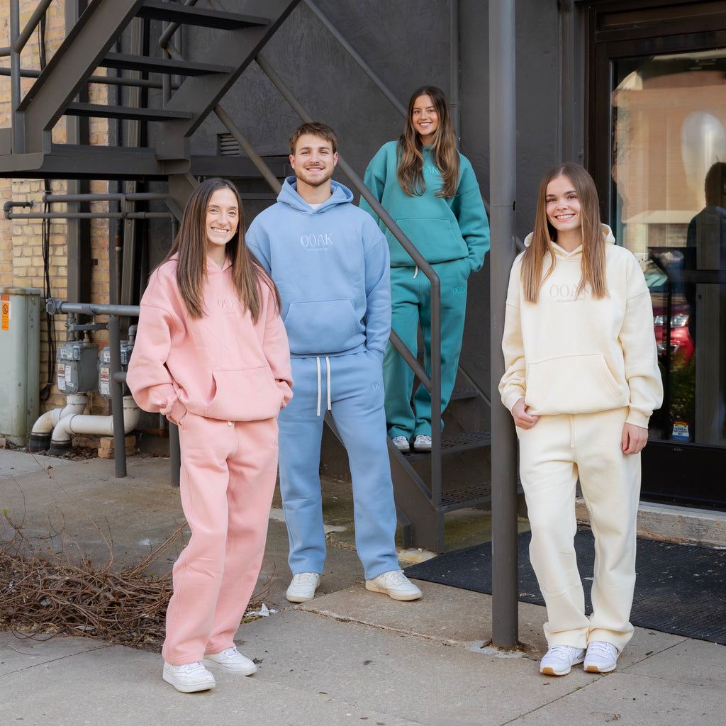 Four people wearing colorful tracksuits standing on a sidewalk.
