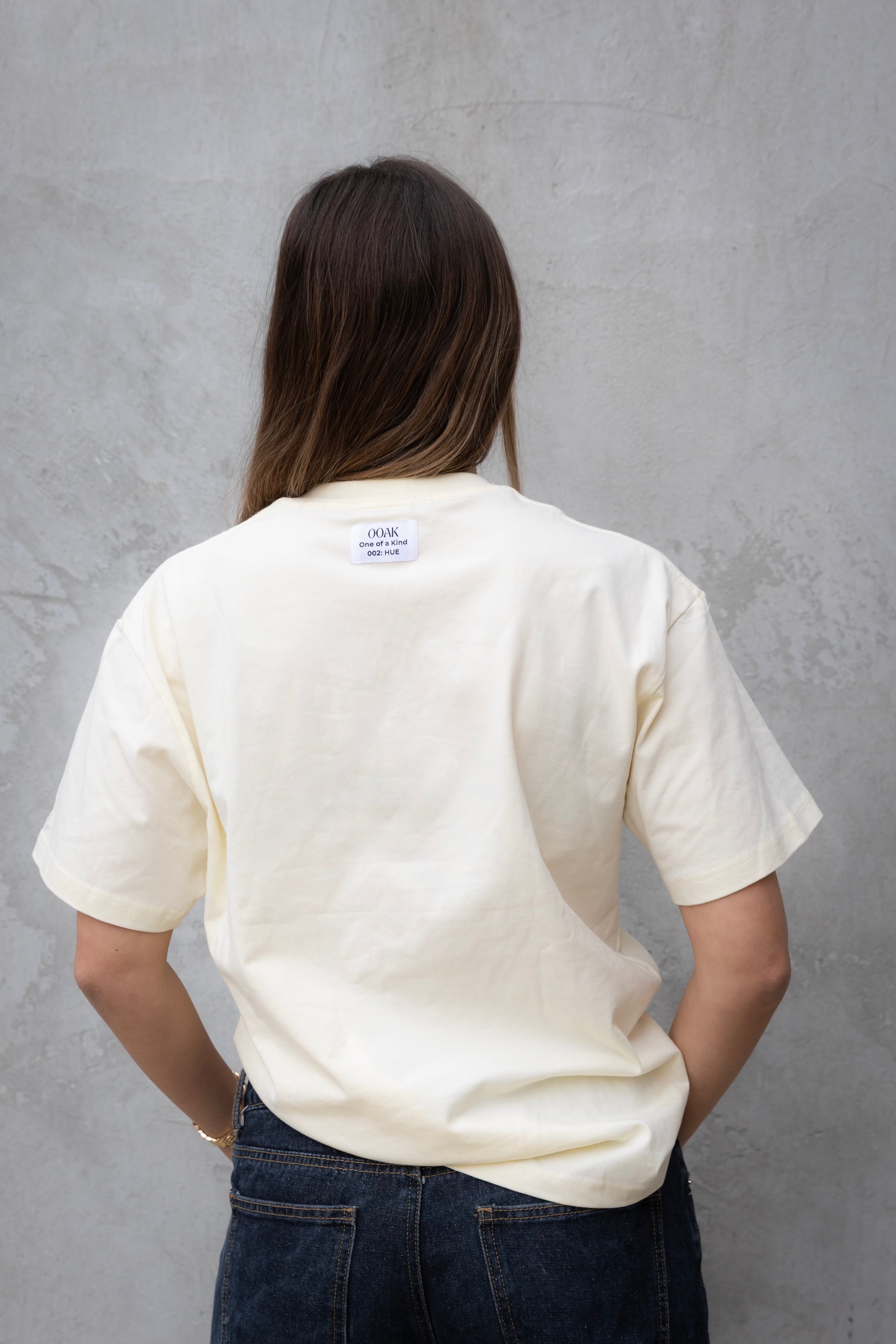 Person wearing a white t-shirt with a visible brand label against a gray background
