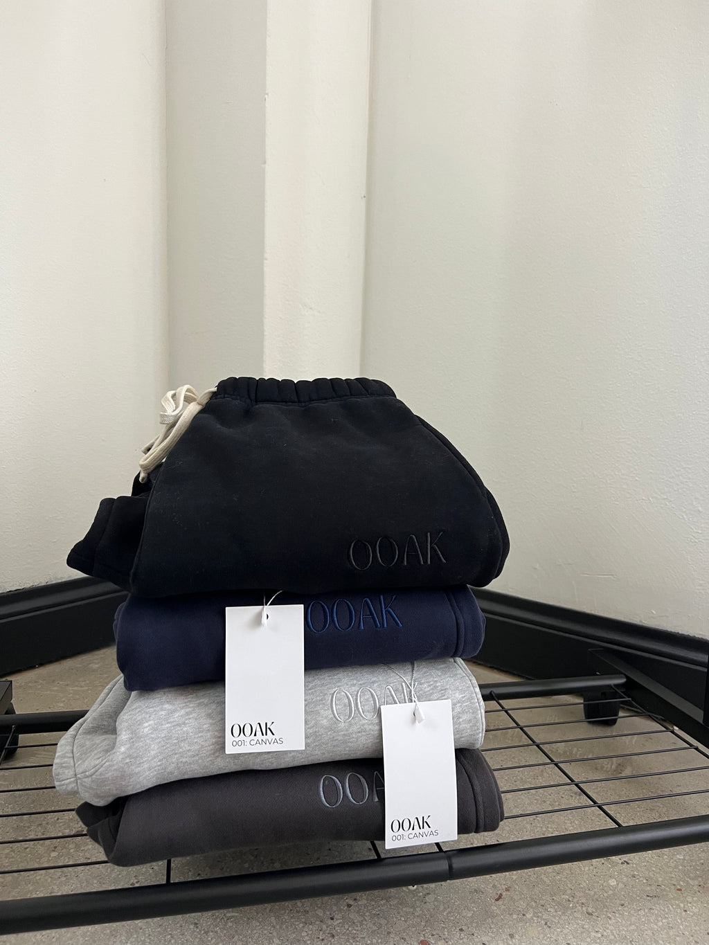Stack of folded clothing with 'OOAK' branding on a metal rack.