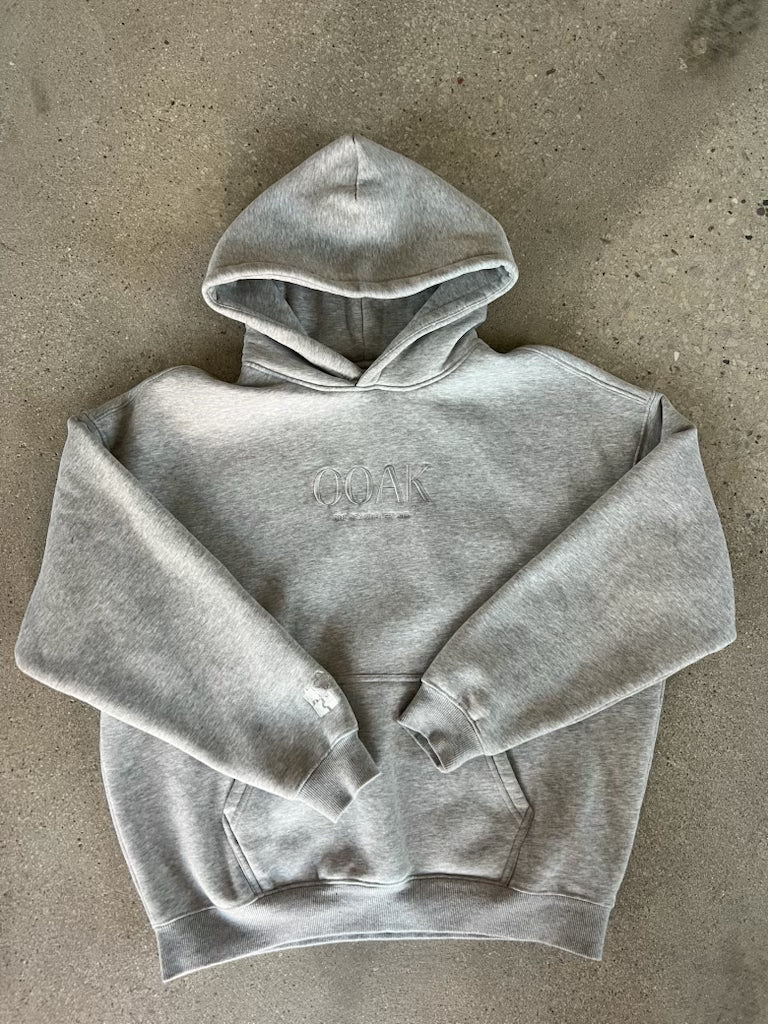Gray OOAK hoodie with a brand logo on a concrete surface