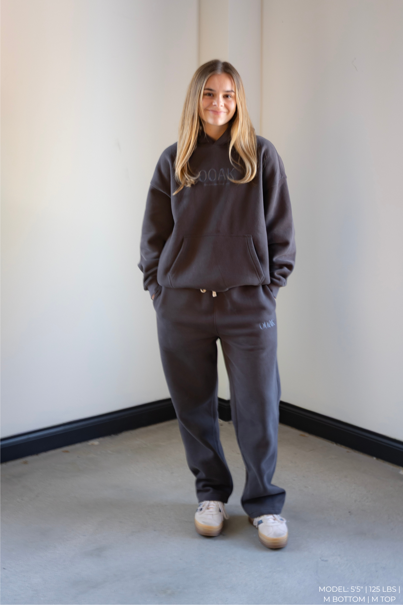 Model wearing a dark gray OOAK hoodie and pants set against a plain wall.