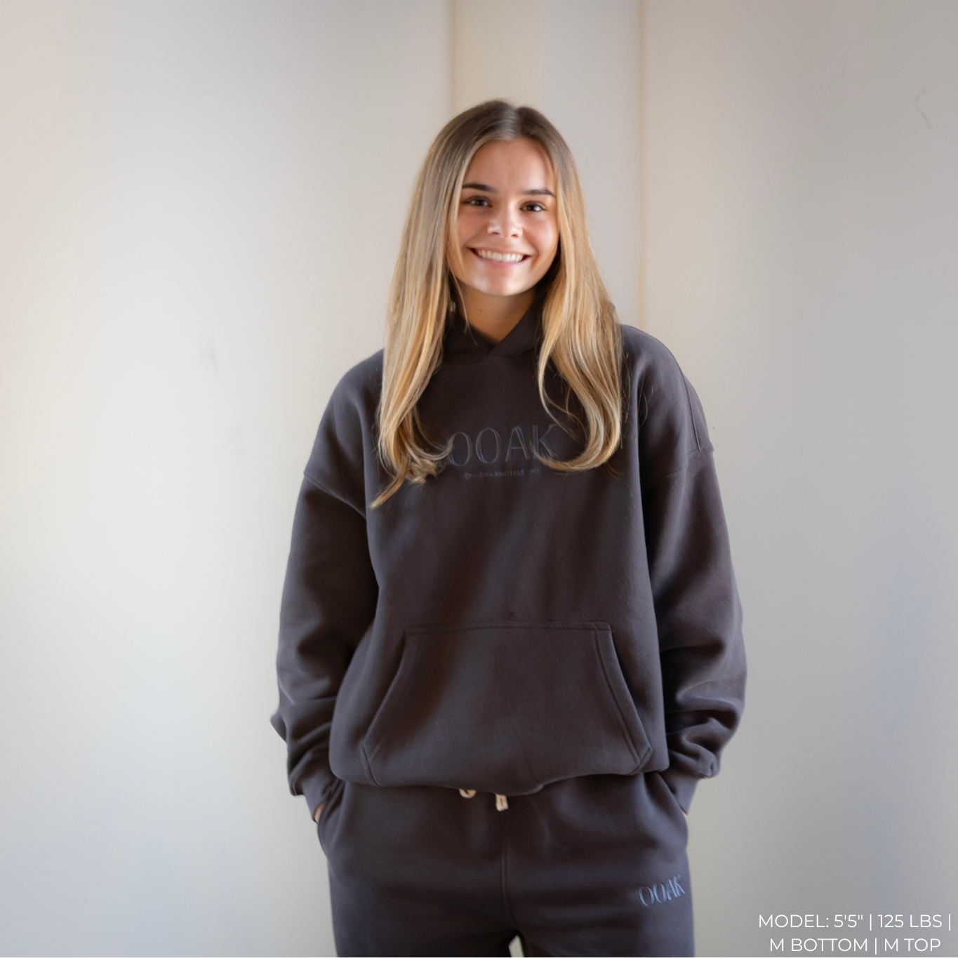 Person wearing a dark gray hoodie with OOAK branding against a plain background