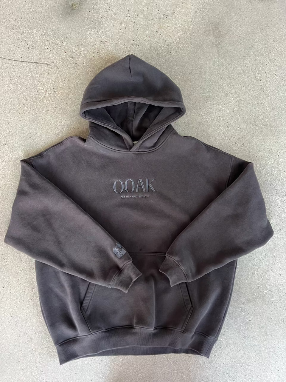 Dark gray hoodie with 'OOAK' branding on a dark gray surface