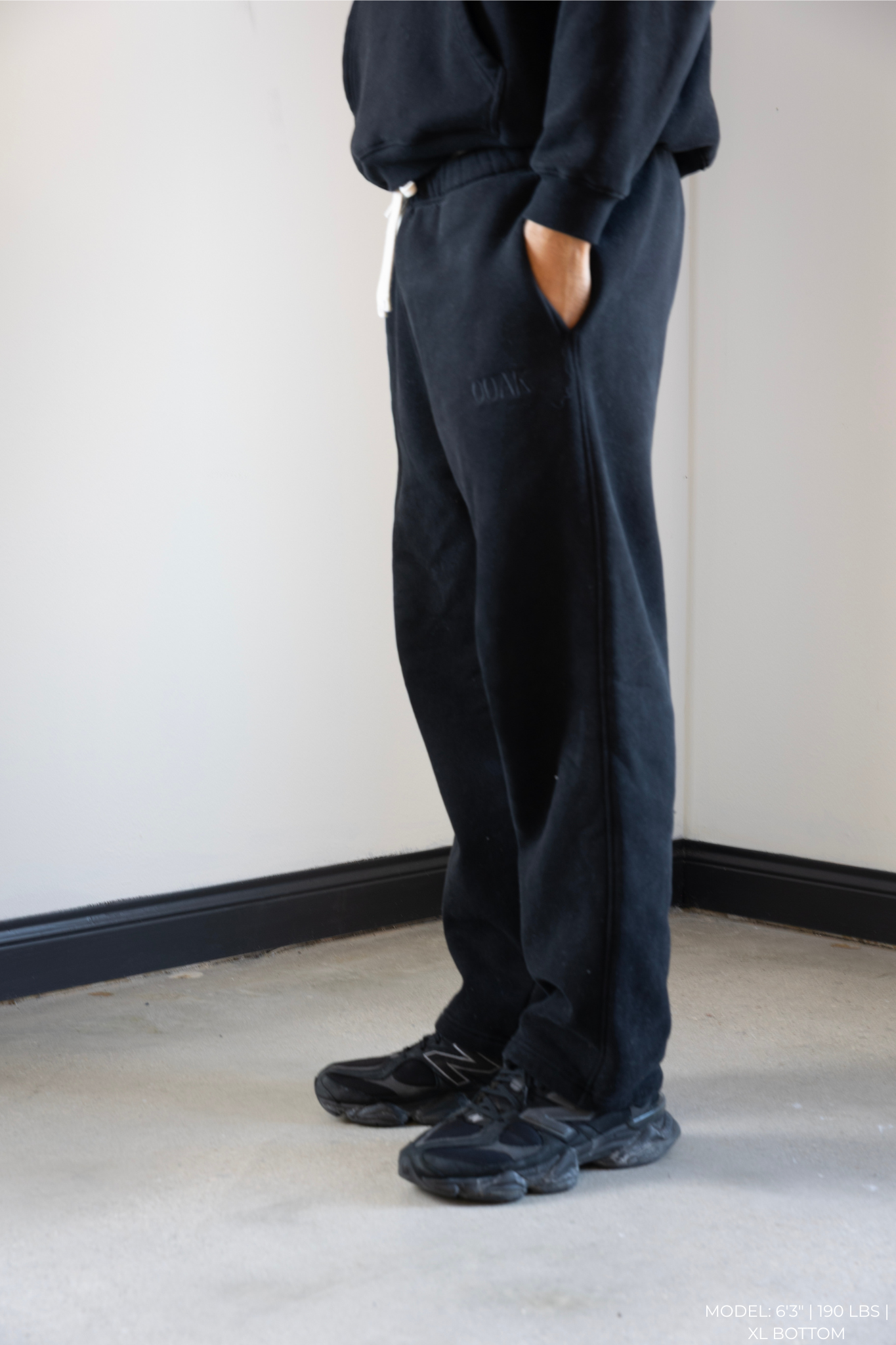 Person wearing black OOAK pants against a plain white wall.